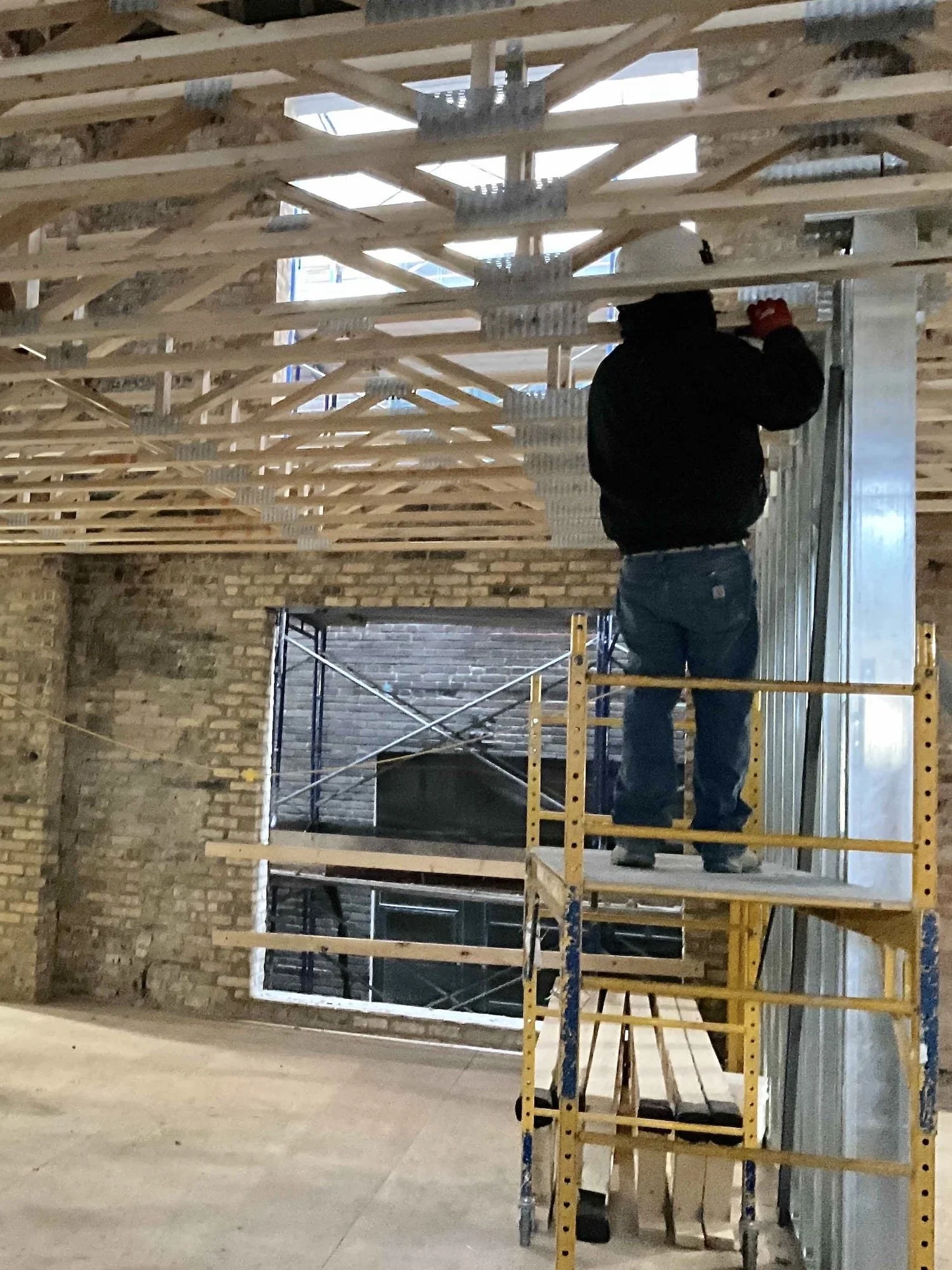 Worker on scaffold installing tall-wall framing inside the Varsity Theater